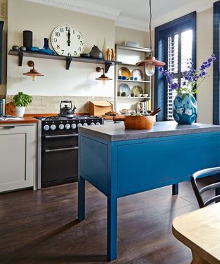 A blue and cream kitchen with a freestanding island and blue shutters, and large black oven