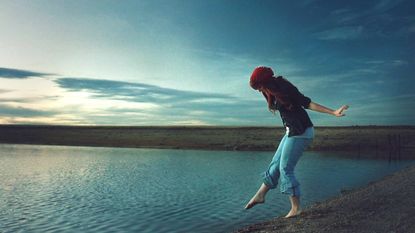 A woman dips her toe into the ocean.