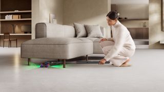 Woman using the Dyson PencilVac to clean under sofa