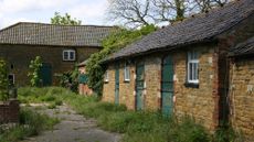 A dilapidated equestrian property, showing overgrown yard and disused stables
