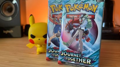 Two Journey Together booster packs beside an angry-looking Pikachu Funko Pop