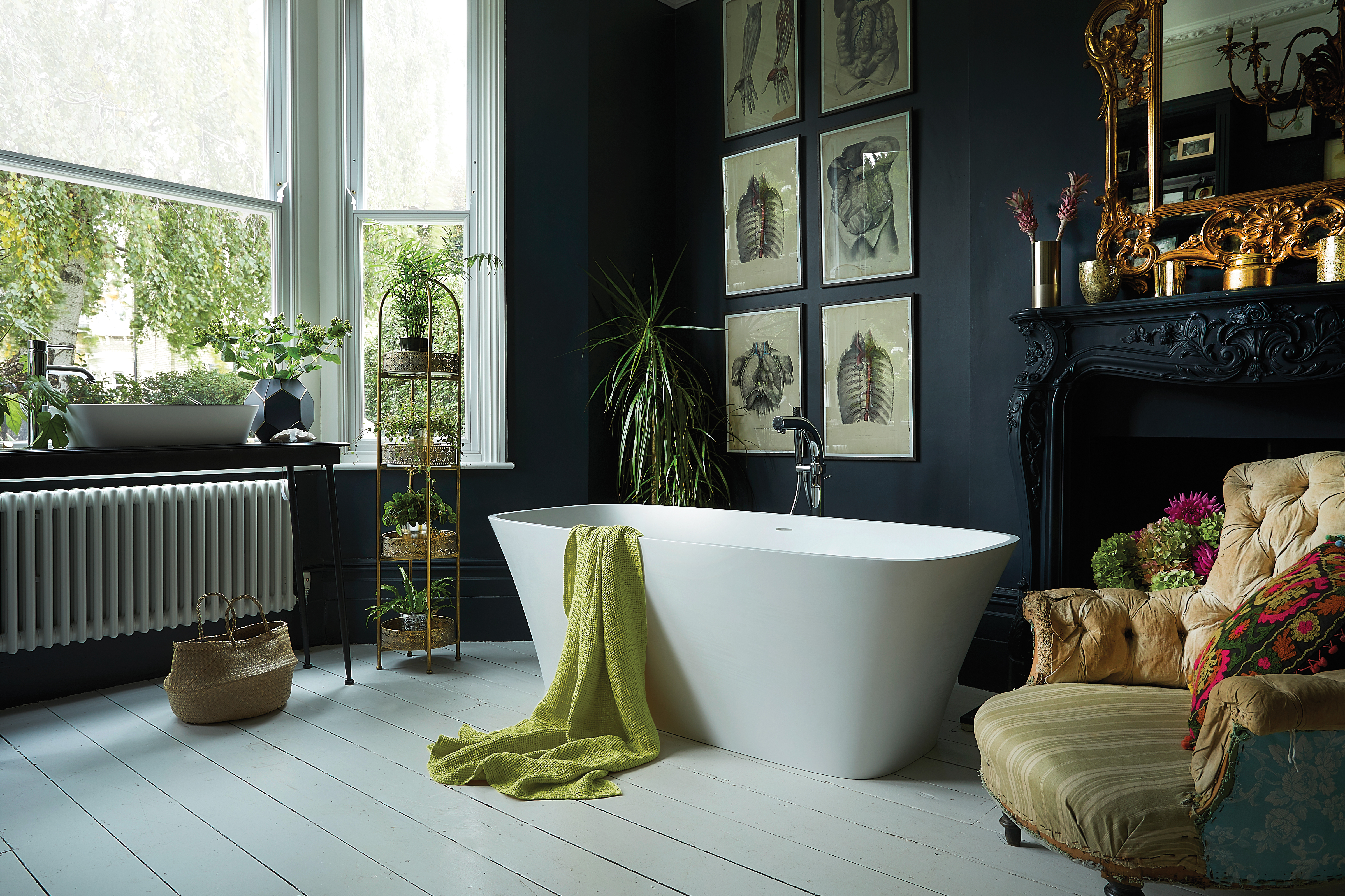 Freestanding bath in dark painted bathroom with gallery wall