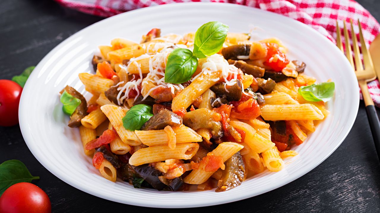 Close up plate of pasta alla norma topped with basil