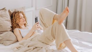 Woman lounging in bed using her phone