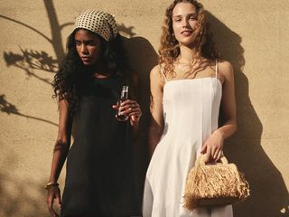 two models wear dresses one wears a black linen shift and the other wears a white dress with more volume in the skirt while posing