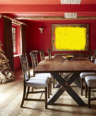 red farmhouse style dining room, artwork, antique table and chairs, herringbone floor