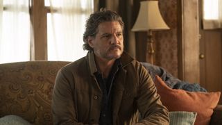 Pedro Pascal in The Last of Us sitting on a sofa in a living room.