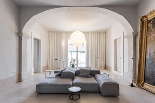 Large room with high ceilings and a grey sofa in the middle