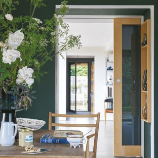 Studio Green coloured wall behind wooden table and chair in room with wooden mirror sliding door