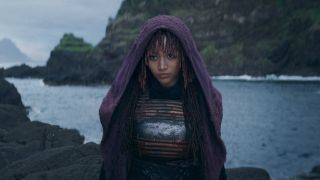 A hooded Amandla Stenberg stands on a beach in The Acolyte.