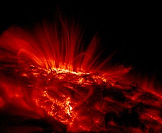 This ultraviolet image of the sun shows large sunspot group AR 9169 as the bright area near the horizon. The relatively cool dark regions have temperatures of thousands of degrees Celsius, in contrast to the bright glowing gas flowing around the sunspots,