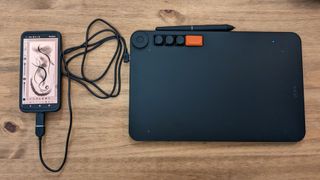 A black Veikk Voila L Pen Tablet sitting on a wooden desk