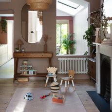 A soft brown-painted living room with a play area zoned with a rug and some toys on top of it