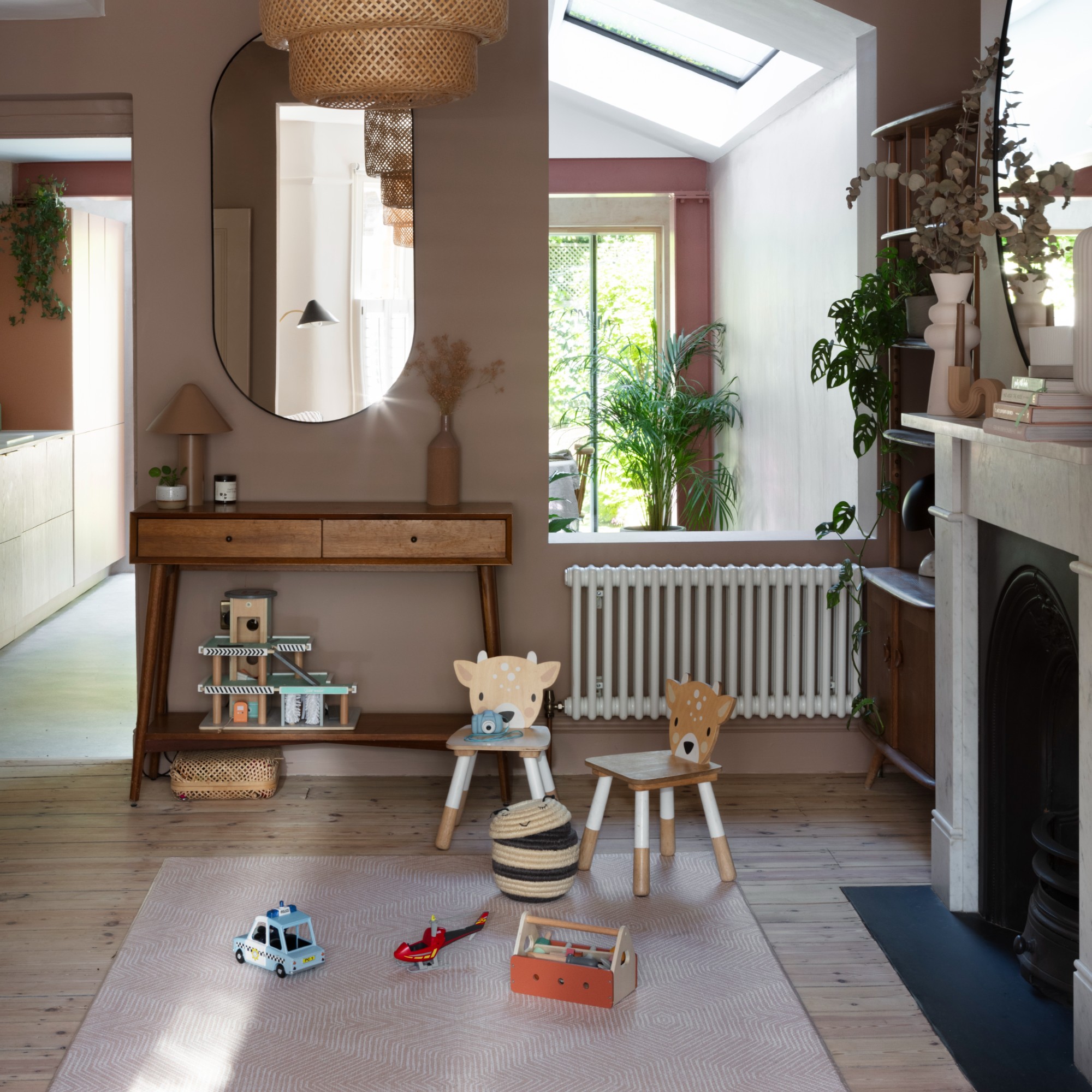 A soft brown-painted living room with a play area zoned with a rug and some toys on top of it