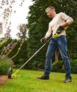 man using a cordless strimmer to edge a lawn