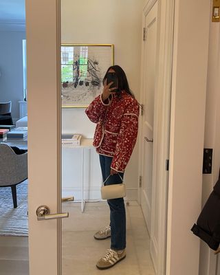 A woman taking a mirror selfie and holding a The Row 90's bag.