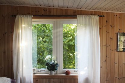 Awning white PVC window with sash curtains and plank wooden wall