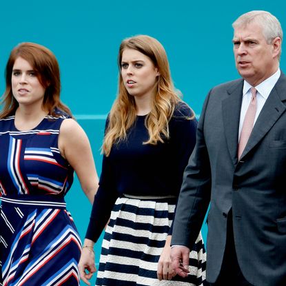 Princess Eugenie and Princess Beatrice wear striped dresses as they walk with their father Prince Andrew, who is wearing a dark suit with a pink tie