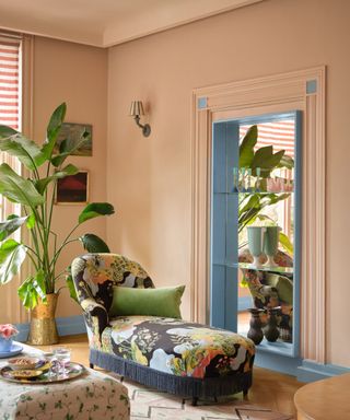 living space with plaster pink walls, floral chaise, blue trim, large houseplant