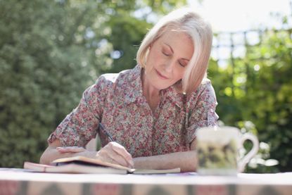 Woman writing in journal at patio table