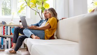 older couple looking at laptop together whilst sat on couch