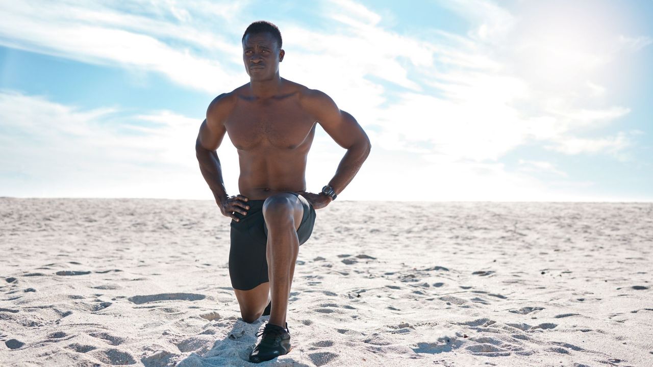 A man performing a lunge on a beach as part of a bodyweight workout