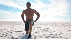 A man performing a lunge on a beach as part of a bodyweight workout