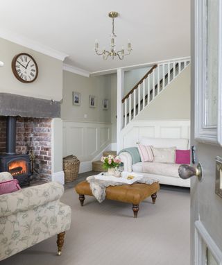 open stairs in living room with sofa, footstool, armchair and stove in fireplace