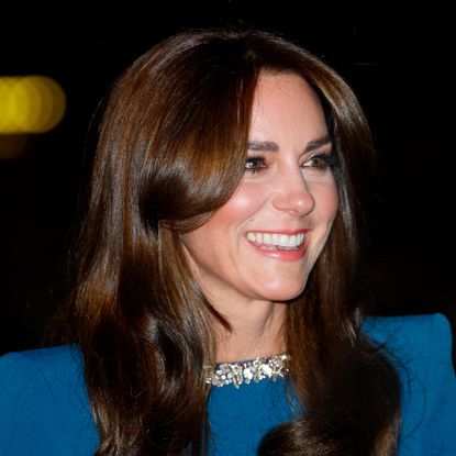 A shoulders up photo of Kate Middleton wearing a blue gown with crystal neckline and smiling