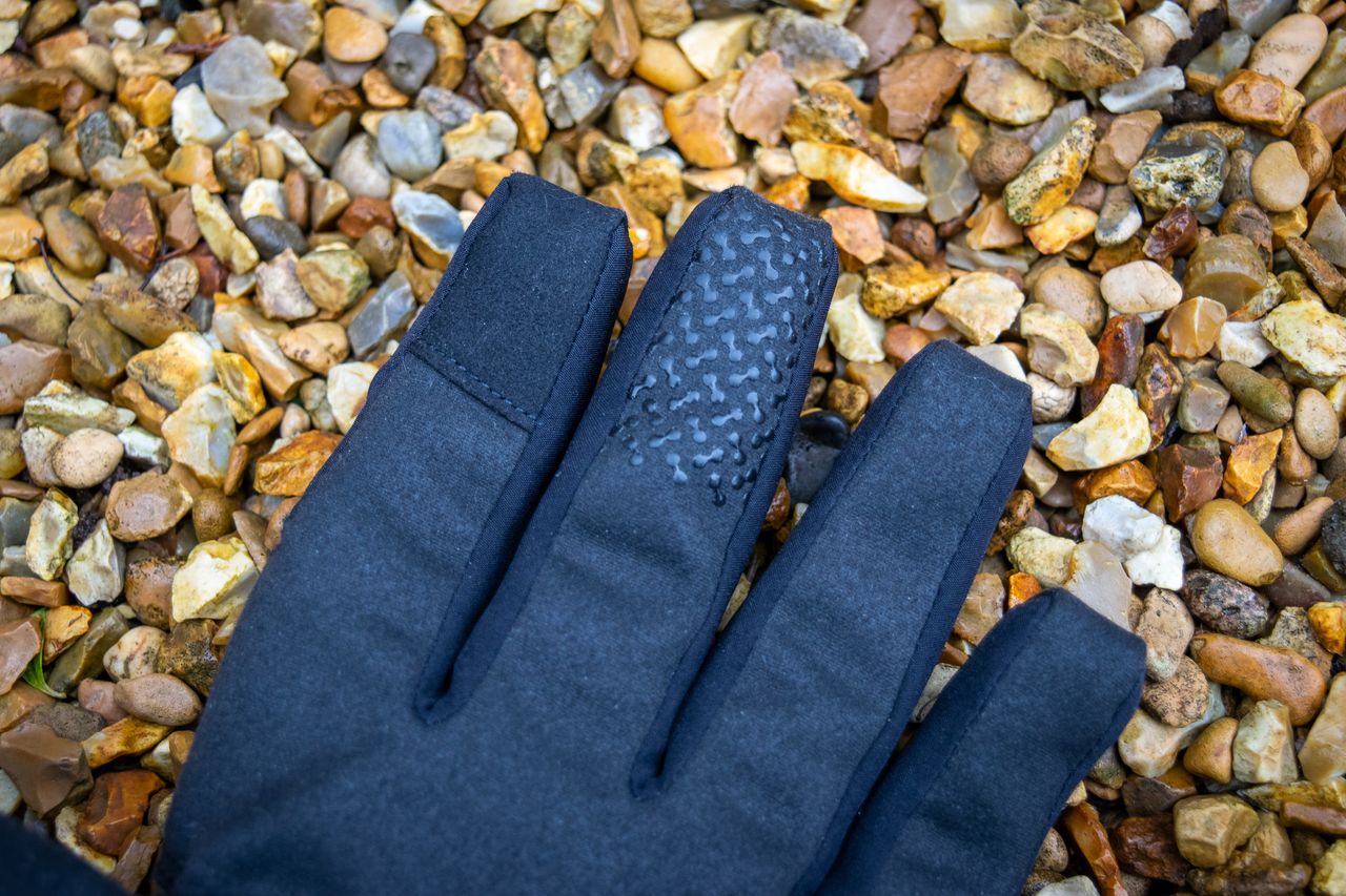 A pair of blue Madison DTE waterproof gloves on gravel