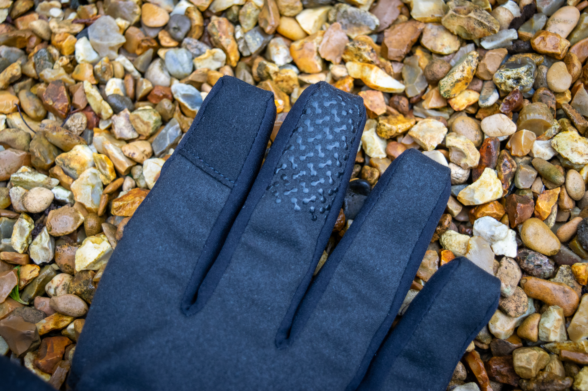 Un par de guantes impermeables azules Madison DTE sobre grava 