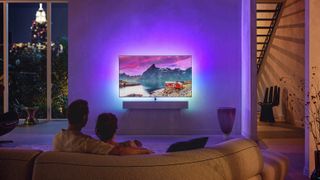 Philip OLED986 TV wall mounted in a living space with two people watching