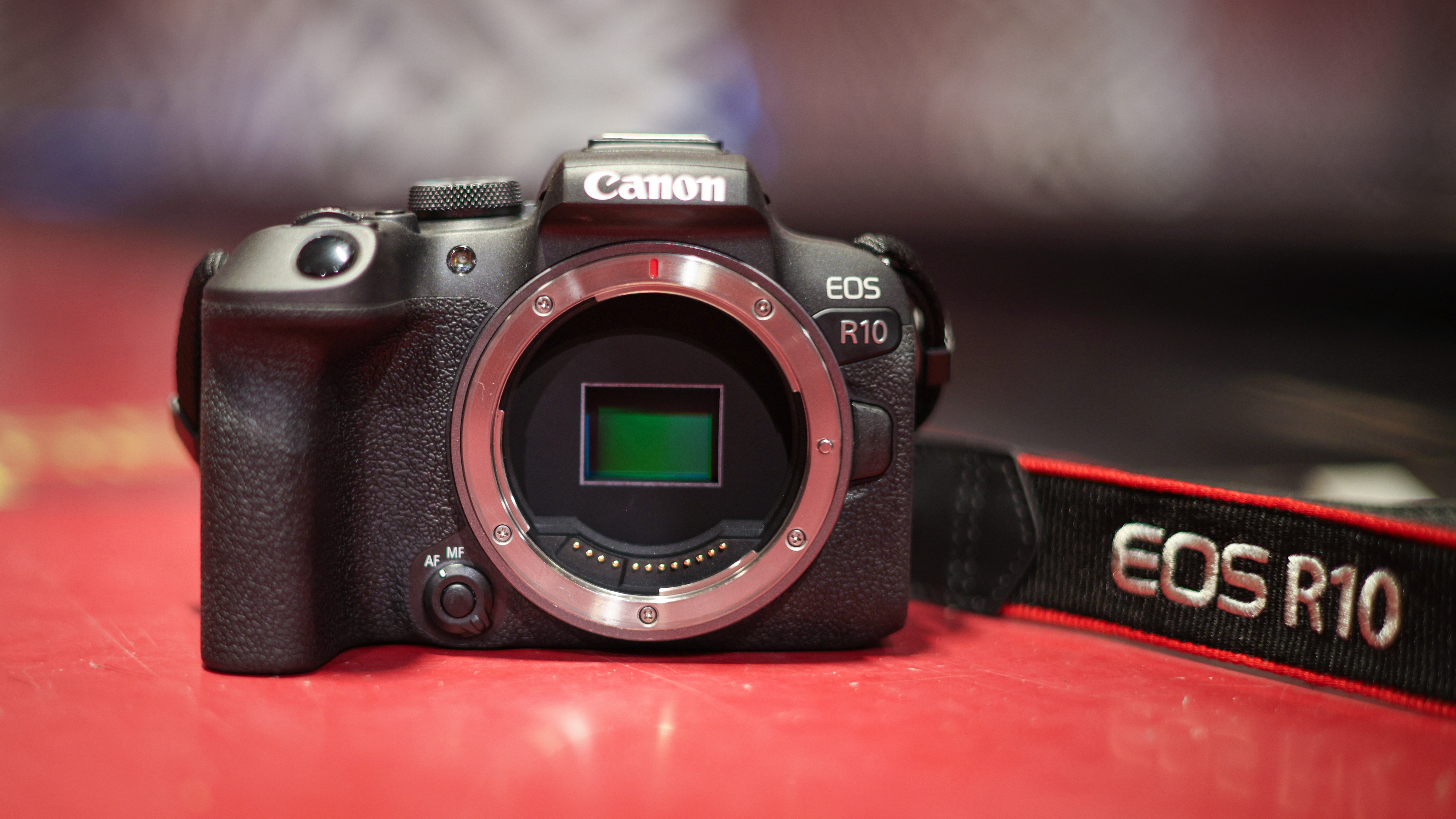 Canon EOS R10 with sensor exposed, sitting on a red surface