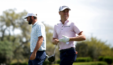 Justin Thomas removes his golf glove after striking his tee shot