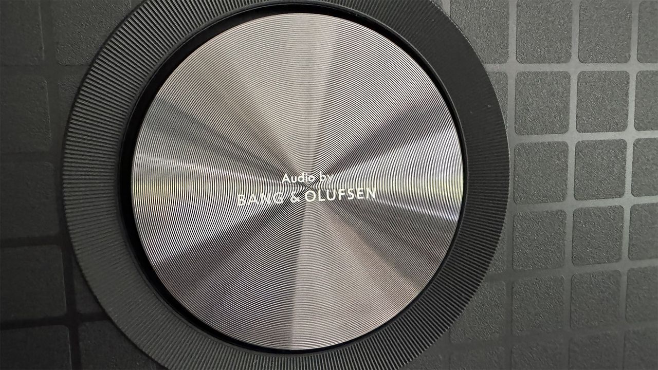 A close-up of one of the circular Bang &amp; Olufsen speakers on the 65-inch TCL C7K Mini LED TV.