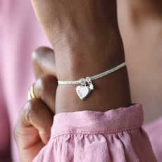 Close up on a womans wrist wearing a heart charm silver bracelet sold at not on the high street