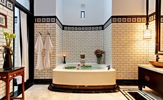 Bathroom featuring a square bath, bathrobes, and tiled walls