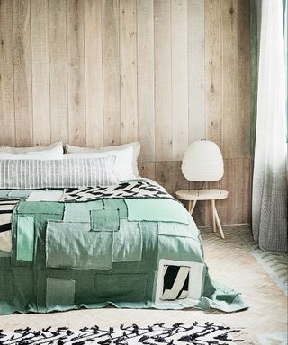 Cozy bedroom ideas featuring rustic wood plank walls and green bedlinen.