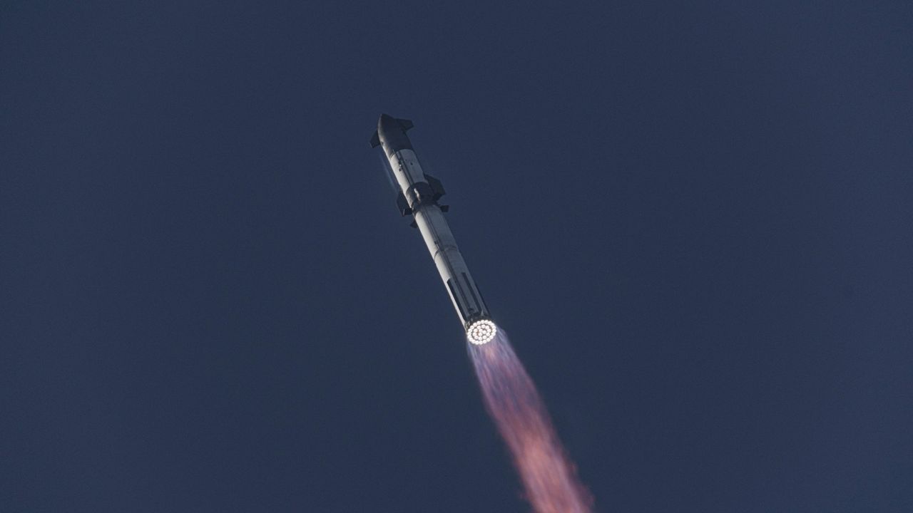 a massive rocket lifts off above a plume of fire at sunrise