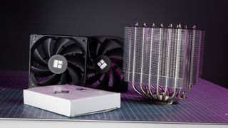 A Thermalright Peerless Assassin 120 SE cooler on a desk with the fans beside it.