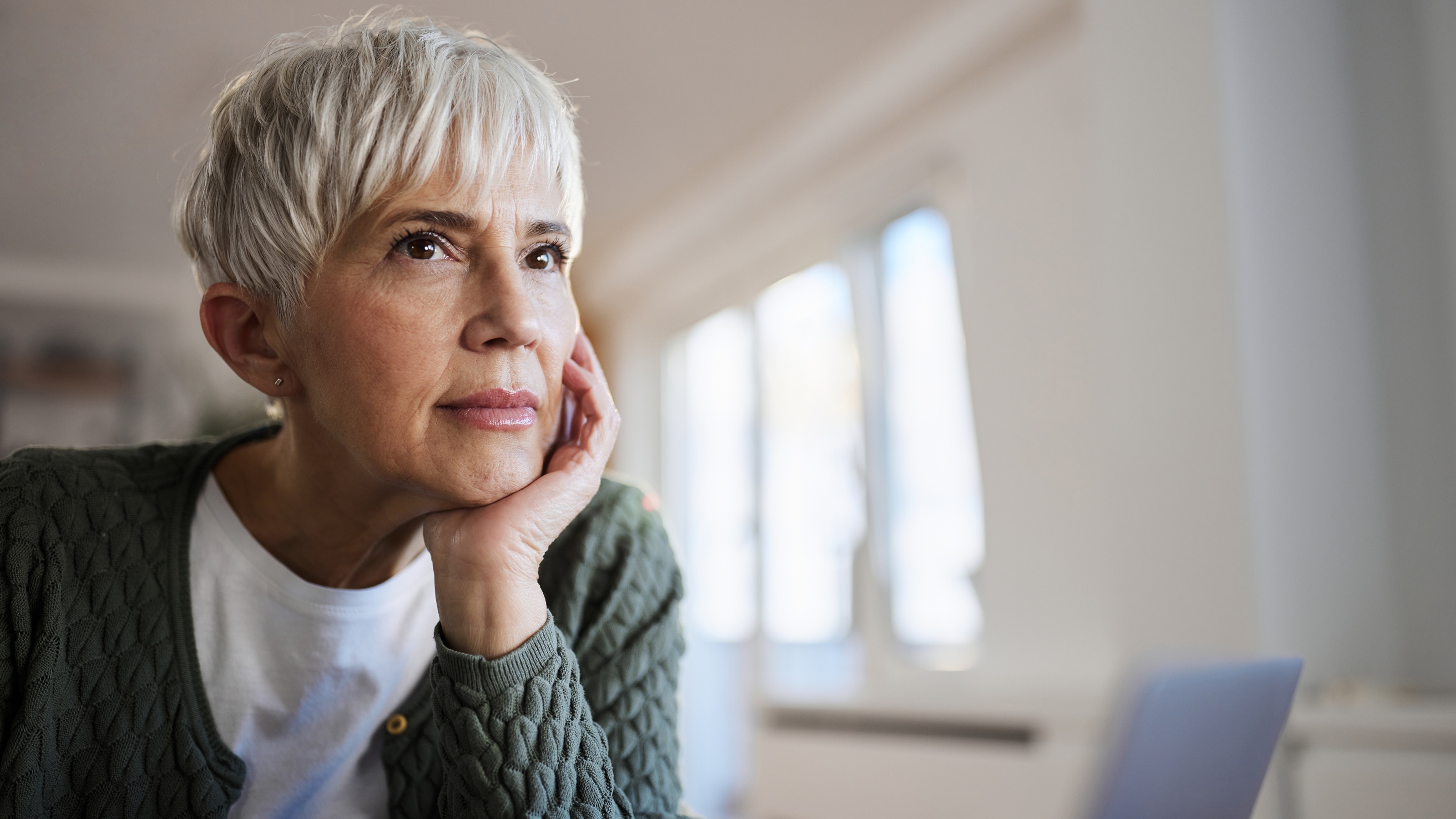 An older woman looks thoughtful as she looks into the distance.