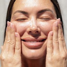 An image of a woman washing her face.
