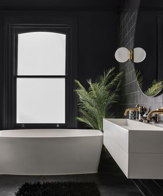 modern bathroom with black walls and floor, white bath and sink