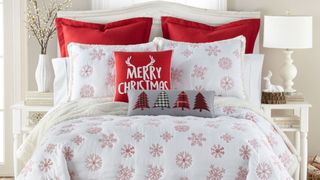 A sherpa quilt Christmas bedding set with embroidered red snowflakes with matching pillow shams made up on a bed.