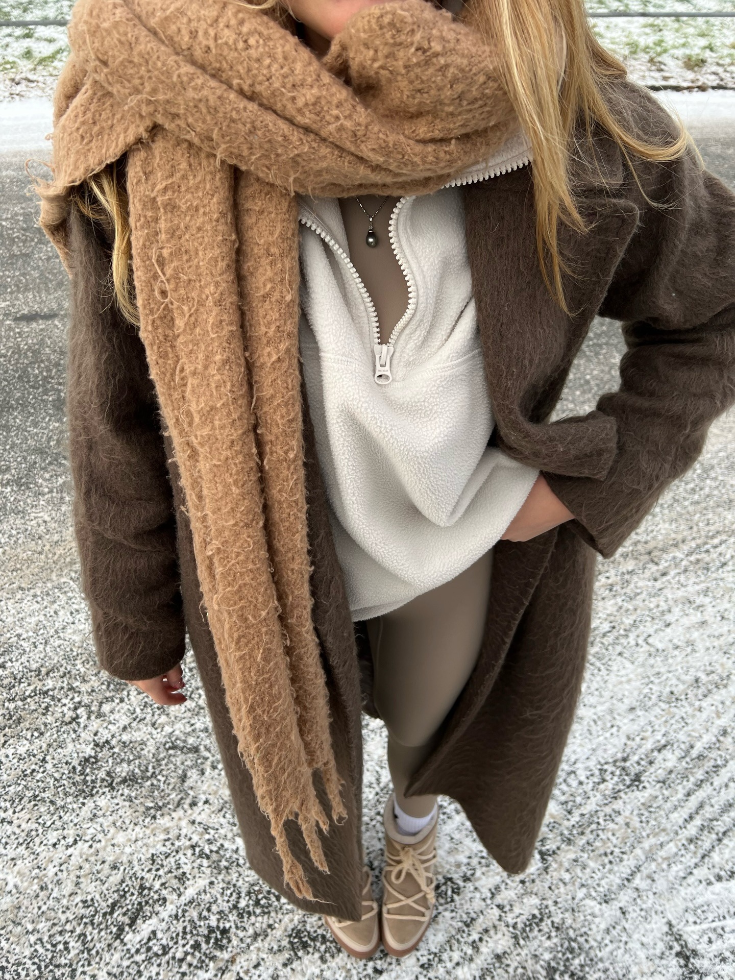 Fashion person Isabella Mayer wears a fleced lined legging outfit. She wears taupe leggings, snow boots a fleece, a taupe top and brown scarf and maxi coat.