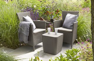 Keter rattan-effect bistro set in a garden with grasses