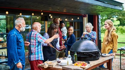 A blended family smiles and laughs together at a family barbecue.