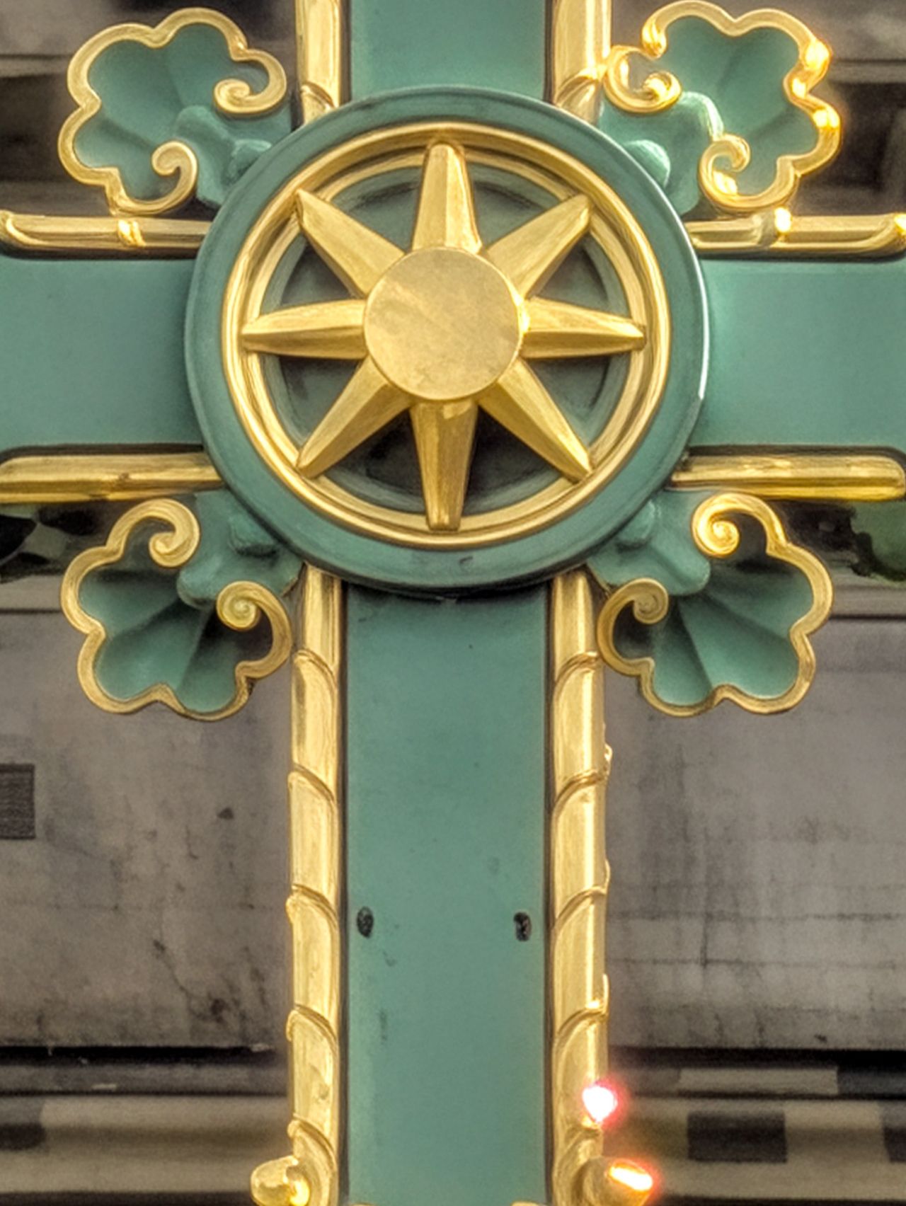 Extreme close-up of the gold star-shaped centerpiece and decorative details on an ornate green cross.