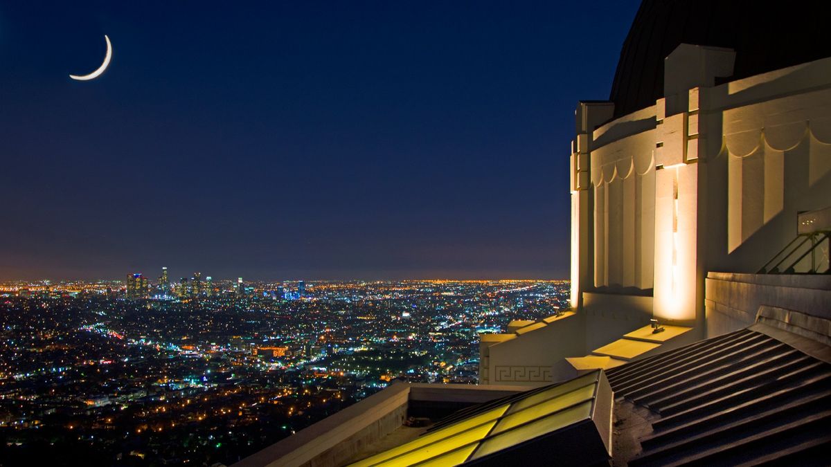 a white building with a large dome in the center lit up at night with city lights behind it