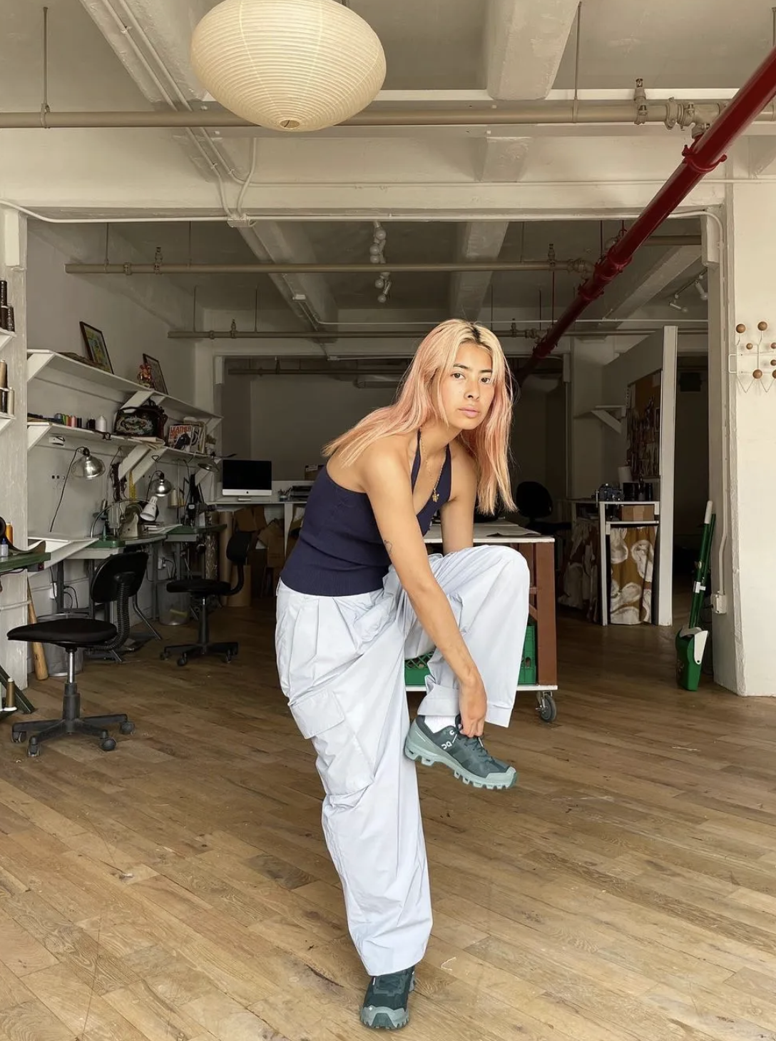 Fashion person himichelleli wears a trending trainer brand 2026. She wears green ON trainers. She wears them with pale blue trousers and a black tank top . This image was recently taken from her Instagram.
